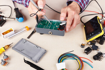 Master checks electrical board with compact oscilloscope at service workplace.