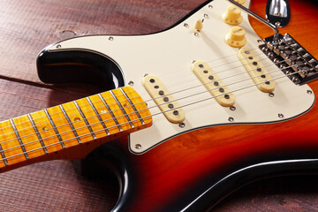 Sunburst guitar closeup on wooden background. Selective focus.