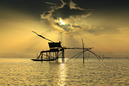 Silhouette Fisherman Catching Fish from square dip net at Pak Pra Canal Phatthalung Province, Thailand