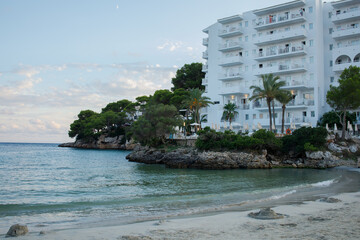 White hotel building and empty Cala Ferrera beach in the evening panoramic view. Cala D'or on Mallorca in Spain.