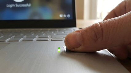 Biometric Authentication: A close-up shot captures the moment of digital security, a fingertip resting on a fingerprint scanner, indicating a successful login to a laptop