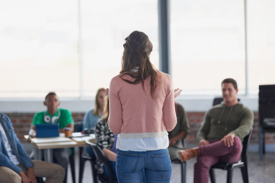 Lecturer, woman and lesson with students at college for exam preparation, learning support or advice. Tutor, back of person and discussion with people in lecture for test feedback and study guidance