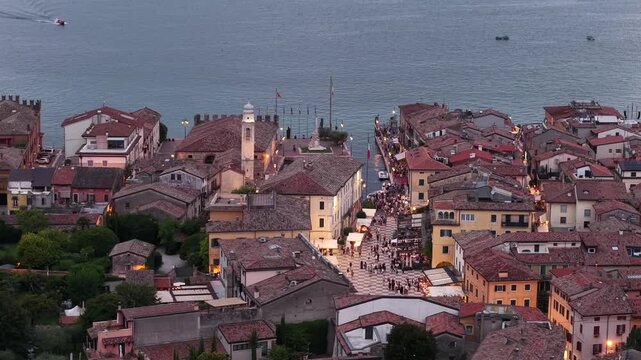 Cinematic aerial view of Lazise, Lake Garda, Italy. Drone footage highlights the historic town, waterfront, and Italian landscape during golden hour at sunset.