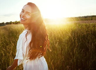 Fototapeta premium Portrait, woman and holiday in field outdoor for summer adventure, explore nature and fresh air. Lens flare, person and space in meadow for tourism, calm morning and vacation getaway in countryside