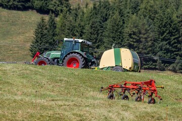 Tractor towing round baler across a grassy field