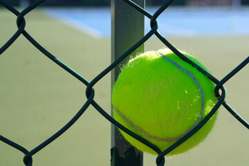 Tennis ball background on a fence with a blurred tennis court in the background. Copy space