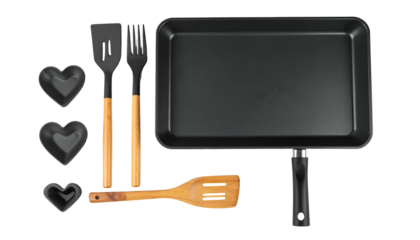 Overhead shot of cooking utensils and pan on black, including heart molds and wooden handles