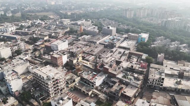 erial view of Pari Chowk, Greater Noida, showing dense low-rise housing, mixed commercial blocks, and urban sprawl fading into haze under Delhi NCR air pollution.