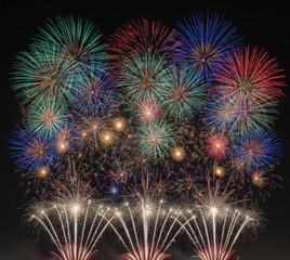 Obraz premium Spectacular fireworks display with blue, gold, and red bursts against a dark night sky. Festive celebration