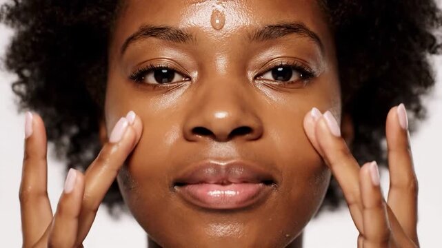 Close-up of person applying clear serum to forehead