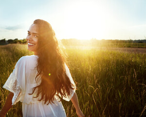Fototapeta premium Portrait, woman and walk with field outdoor for summer adventure, explore nature and holiday. Lens flare, female person and space in meadow for trip, calm morning and vacation getaway in countryside