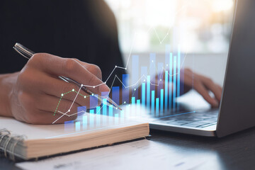 Business professional analyzing financial data and market trends with digital growth charts overlaid on a notebook and laptop, demonstrating strategic planning, performance monitoring