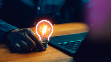 Innovative energy and idea concept with glowing light bulb and lightning bolt icon on office desk background, symbolizing inspiration and creative brainstorming.