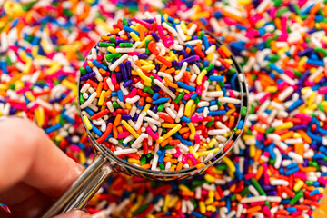 Hand holding scoop of rainbow sprinkles