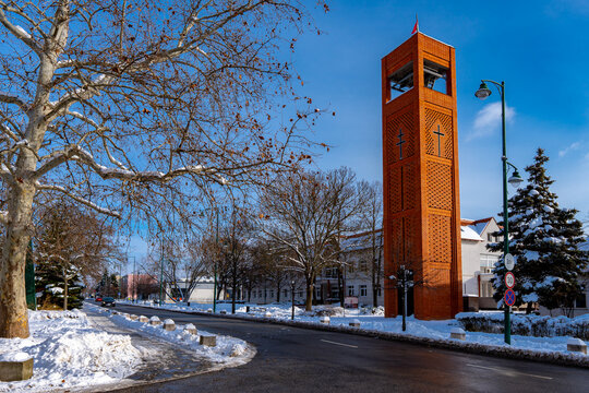 Vertical brick church bell tower rising above a quiet urban street in winter. 
Capistrano-Hunyadi Memorial Tower, Dabas, 
