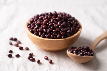 Azuki beans, Adzuki bean or red mung beans in wooden bowl and spoon on white fabric background, Food ingredients in many Chinese dishes and filling in Japanese sweet