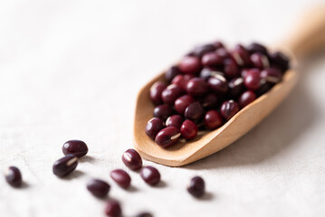 Azuki beans, Adzuki bean or red mung beans in wooden spoon on white fabric background, Food ingredients in many Chinese dishes and filling in Japanese sweet