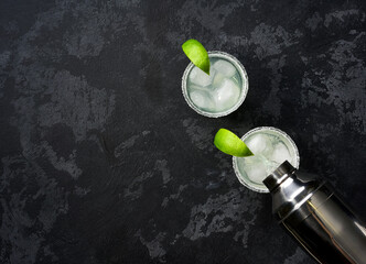 Margarita cocktail is poured from a shaker into a glass with a slice of lime and an edge of salt along the edg, top view.