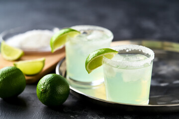 Key lime margarita garnished with fresh lime and salt in margarita glass on metal tray.