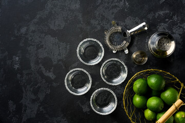 Ingredients and props for making Margarita cocktail with lime and ice on a black  background. Top view with copy space.