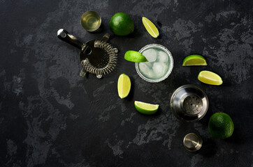 Ingredients and props for making Margarita cocktail with lime and ice on a black  background. Top view with copy space.