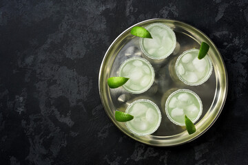metal tray with traditional cocktail Margarita served in salt rimmed tumbler over ice and garnished with a lime.Top view.
