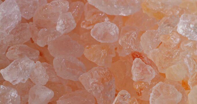 Close-up macro view of coarse rose-colored Himalayan salt grains gently sparkling under soft lighting.