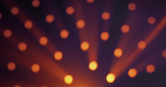 Warm yellow light shines through round holes in a black background