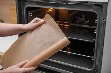 A roll of waxed brown baking paper held in a cook's hand
