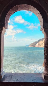 Scenic video of an ancient stone arch overlooking the sea in Portovenere, Liguria, Italy. The historic coastal structure frames a breathtaking Mediterranean seascape with rugged cliffs and deep blue