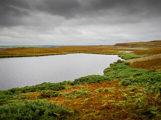 Moorland landscape with a loch under a cloudy sky in Scotland