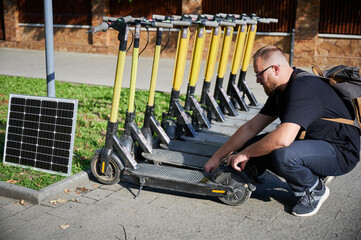 Man connects solar panel to electric scooter for charge, highlighting practical application of sustainable renewable energy. Concept of integration of eco-friendly technology in urban transportation.