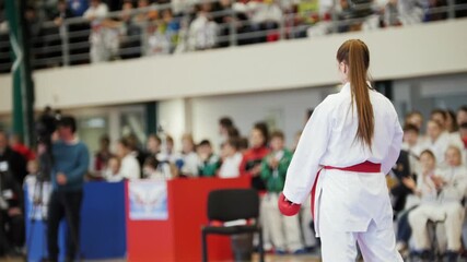 Young karate athlete stands before crowd in competition