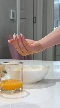 pour the whites and yolks by hand chef separating egg by carefully pouring egg white into stainless steel bowl while keeping yolk aside in glass cup during kitchen prep