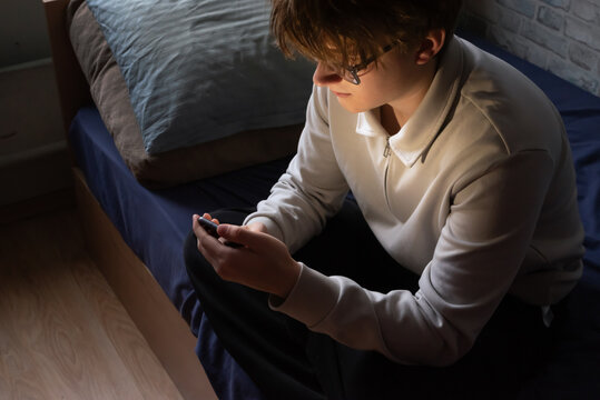 Unhappy stressed teenager boy sitting with smartphone - Powered by Adobe