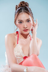 Elegant Thai model in white lace corset top with red ribbon accents poses seductively, arms raised gracefully, glossy skin glowing under studio lights, ruffled mini skirt and cherry earrings 