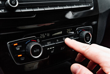 Fototapeta premium Hand pressing the button for interior heating and heated seats in the car in winter.