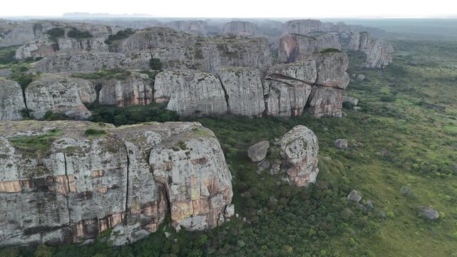 Cinematic golden hours flight over the ancient stone giants of Pungo Andongo, Malanje, Angola, Africa, highlighting the contrast between dark monoliths and green plains