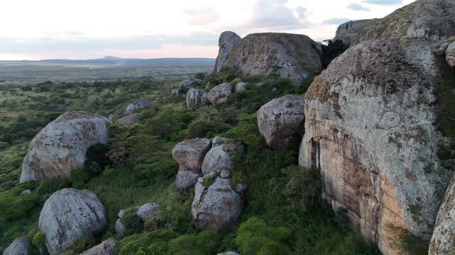 Cinematic flight over the ancient stone giants of Pungo Andongo, Malanje, Angola, Africa, highlighting the contrast between dark monoliths and green plains