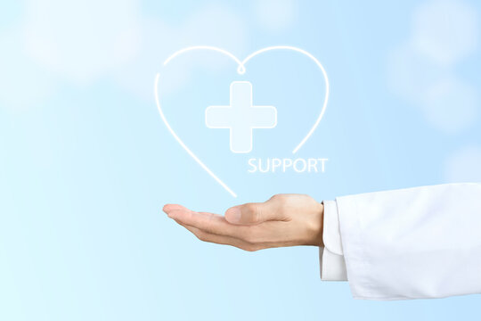 ハートで囲まれた医療マークとサポートの文字を掲げる白衣を着た人物の手