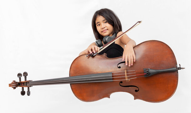 Asian girl in black dress playing cello and shouting with headphone. Concept for music education, child prodigy, emotional performance, and creative talent