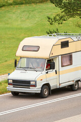 Retro campervan driving past green fields on highway