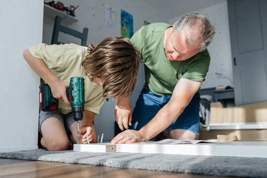 Father and son assembling furniture at home for improvement