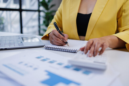 Business financing accounting banking concept. Businesswoman hand doing finances and calculate on desk about cost at home office. Woman working on desk with using calculator, finance accounting.

 - Powered by Adobe