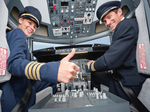 Pilot and co-pilot giving thumbs up in airplane cockpit