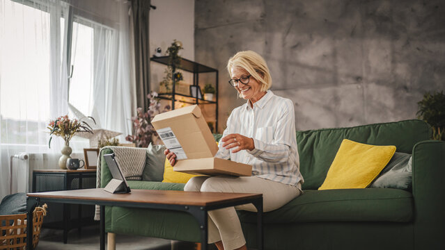 Mature sit on sofa woman work from home open delivery package