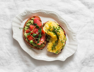 Breakfast, brunch, snack sandwiches with avocado, omelette and lightly salted salmon on plate on a light background, top view
