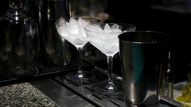 Bartender makes two glasses of cocktail Aperol spritz on bar counter, adds fresh orange slices. Typical alcoholic Italian beverage, aperitif made with Prosecco sparkling white wine and ice cubes