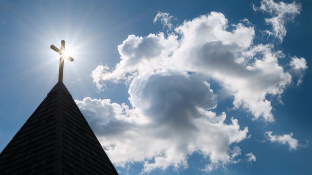 Silhouette of a church steeple with a cross against a bright blue sky. Sun shining through the cross with drifting clouds. Christianity and faith concept. Copy space for text
