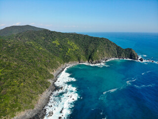 Obraz premium Aerial view of crescent bay with turquoise water and forested cliffs along the Shikoku coast Japan